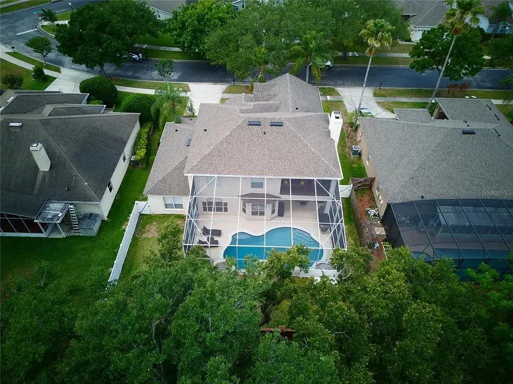 Aerial view of completed shingle roof installation over a screened pool home in Orlando
